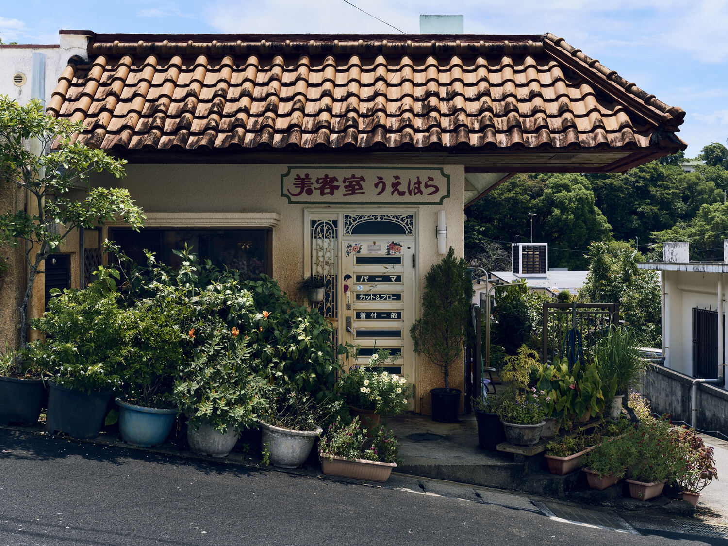 緑に包まれた瓦屋根の小さな美容室