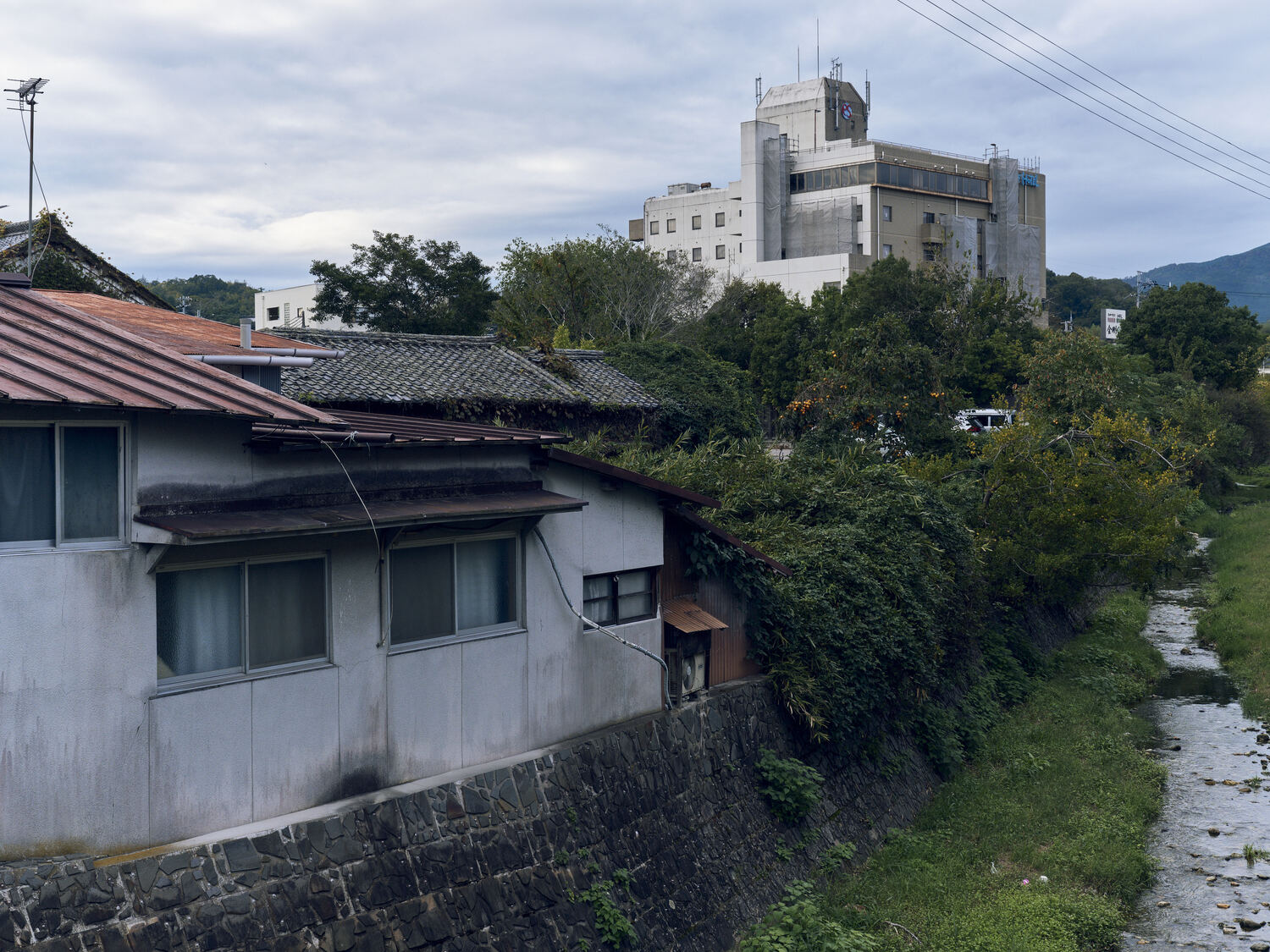 川沿いに重なる暮らしと白の建物
