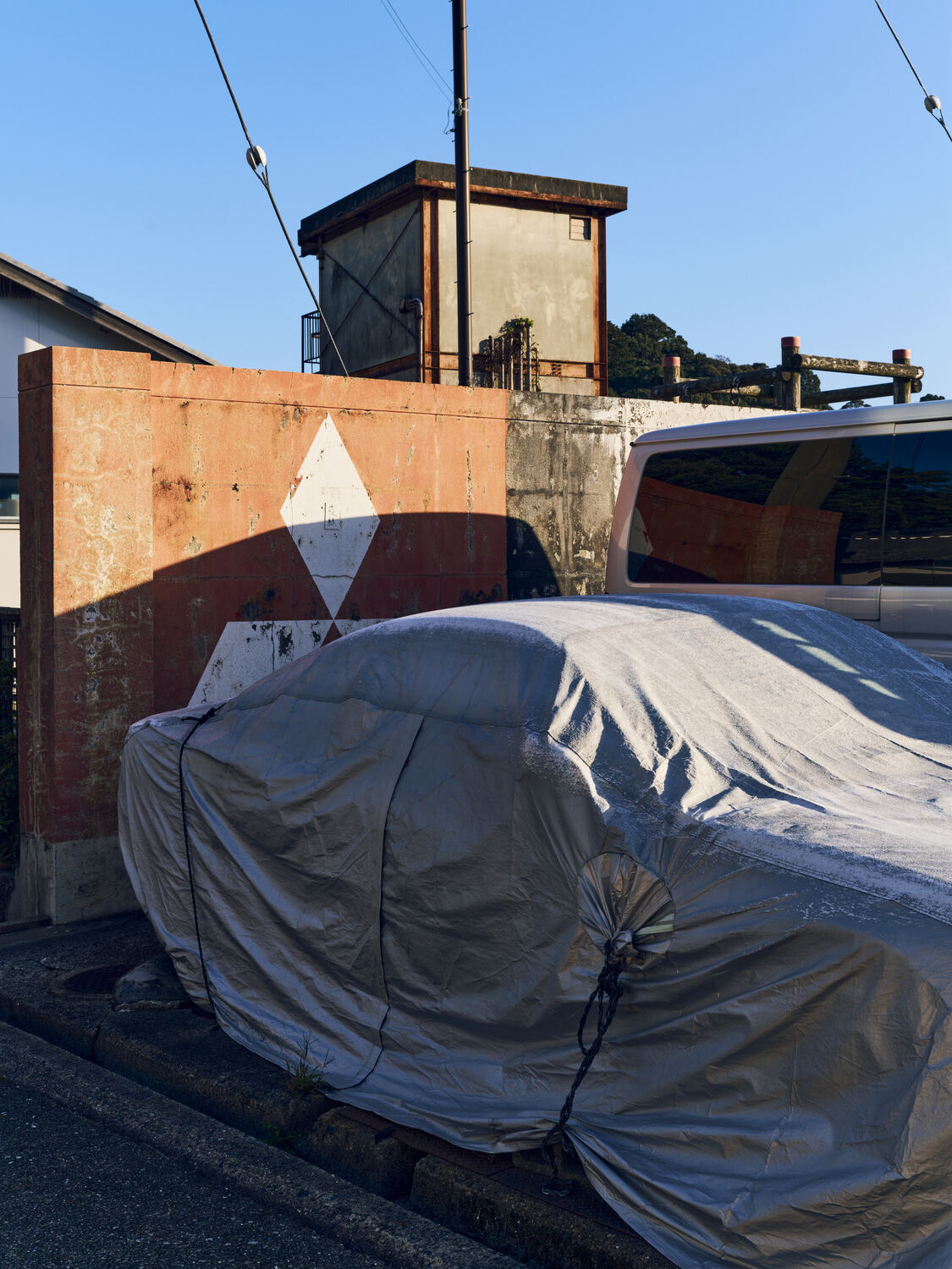 カバーに覆われた車と目的がわからない建物