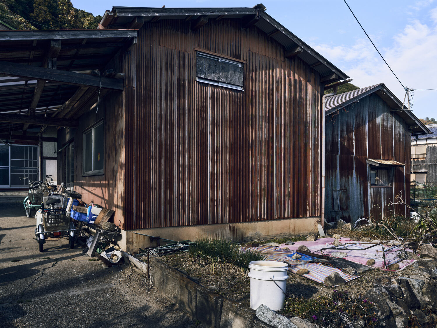 錆色の家と三輪車と畑